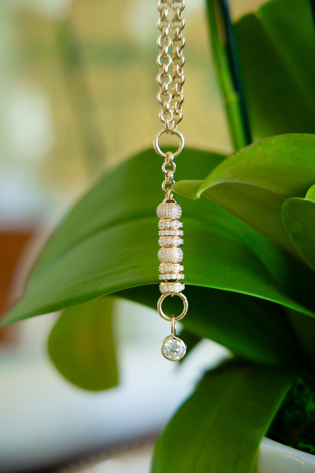 Necklace with a beaded pendant hanging on green leaves
