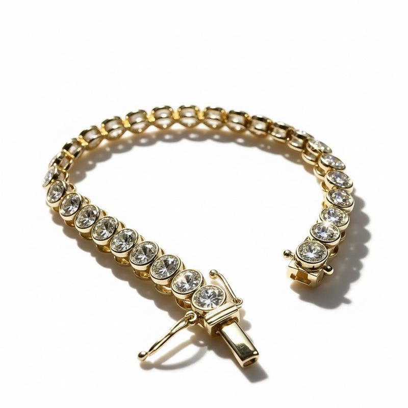 A gold tennis bracelet adorned with clear round and rectangular gemstones, displayed on a white surface with dramatic diagonal shadows.