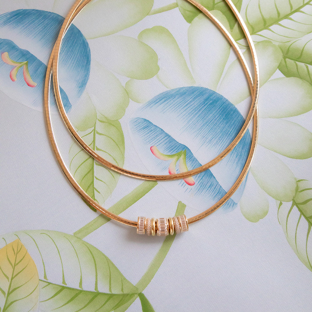Gold necklace on a floral-patterned surface