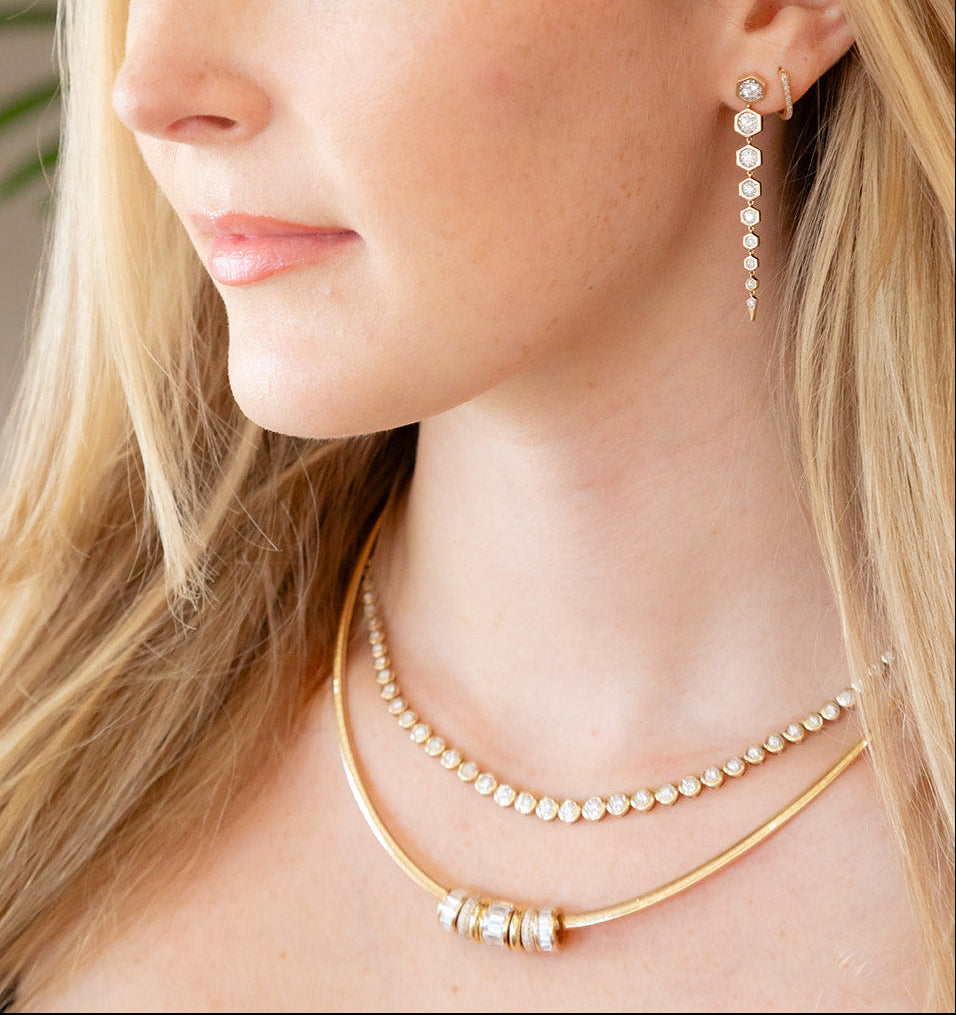 Close-up of a woman wearing a gold necklace and diamond earrings. Palm Beach based jewlery designers